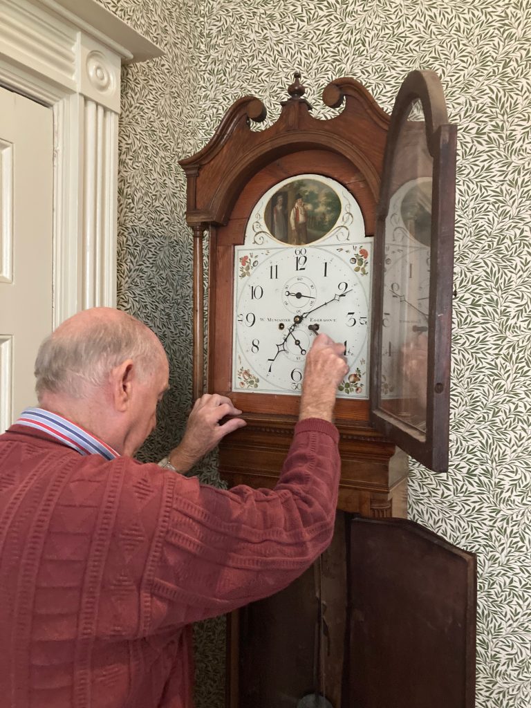 An man is winding a grandfather clock